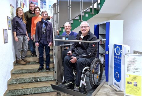 Behindertenbeauftragter Rudi Bamberger und Bürgermeister Dr. Ralf Göck (v.l.n.r.) weihten den Treppenlifter mit der Büchereibelegschaft um Büchereichef Christian Sauer (Mitte) und seine Mitarbeiterinnen Luisa Uhrig (l.) und Ute Roes sowie Kai Rill ein