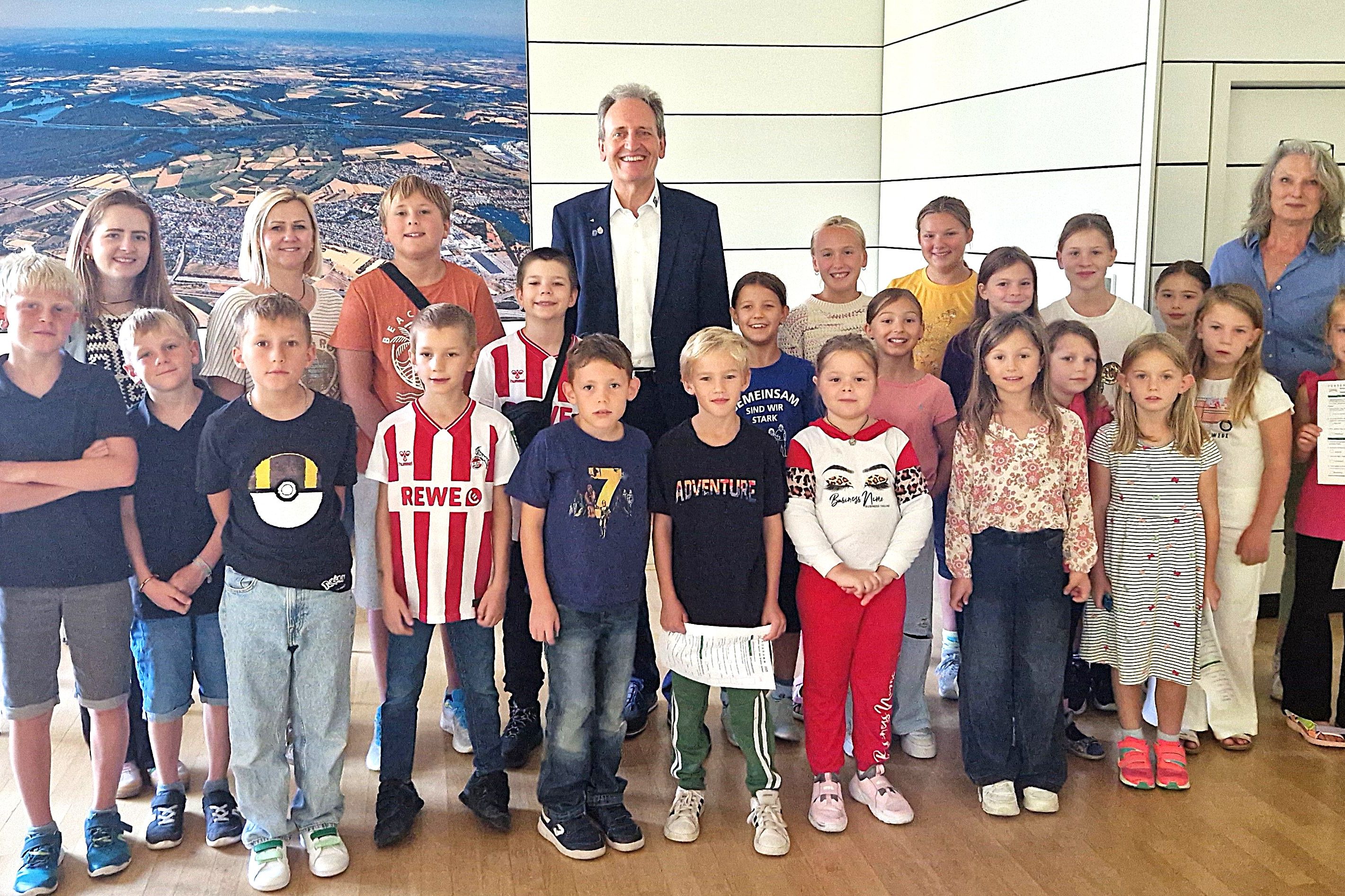Alle Ferienkinder in Startstellung zur Rathaus-Rallye mit Bürgermeister Dr. Ralf Göck und Marion Thüning (rechts), gesamtverantwortlich für das Kinderferienprogramm 2025, und Marie Schäfer mit Ivona Szutra im Sitzungssaal des Rathauses